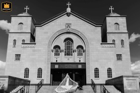 At St. Sophia Greek Orthodox Church in Washington D.C., the bride enters the sanctuary, framed from behind within the striking symmetrical architecture of the church entryway.
